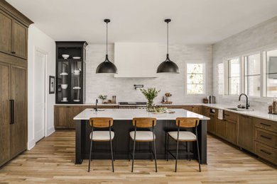 Inspiration for a mid-sized transitional l-shaped medium tone wood floor open concept kitchen remodel in Charlotte with paneled appliances, an island, white countertops, an undermount sink, shaker cabinets, medium tone wood cabinets, quartz countertops, white backsplash and ceramic backsplash