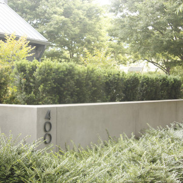 Modern concrete site walls + soft textured evergreen hedge for privacy