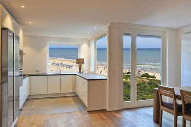 Small trendy u-shaped light wood floor and brown floor eat-in kitchen photo in Jacksonville with an undermount sink, flat-panel cabinets, white cabinets, stainless steel appliances and no island