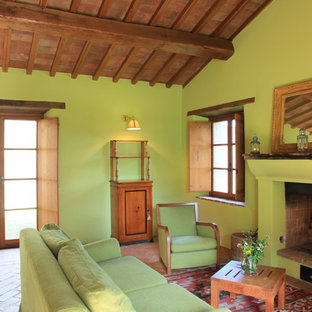 Fernseherloses, Offenes Mediterranes Wohnzimmer mit grüner Wandfarbe, Terrakottaboden, Kamin und verputztem Kaminsims in Rom