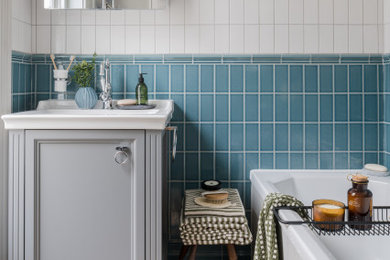 Photo of a small contemporary grey and white bathroom in Sussex with shaker cabinets, grey cabinets, a built-in bath, blue tiles, ceramic tiles, grey walls, laminate floors, a submerged sink, solid surface worktops, brown floors, white worktops, a dado rail, a single sink and a freestanding vanity unit.