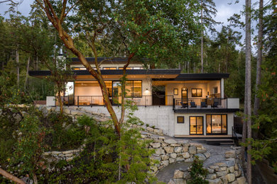 Contemporary beige house exterior idea in Vancouver with a black roof