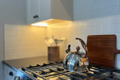 Mid-sized u-shaped linoleum floor and gray floor enclosed kitchen photo in Boston with an undermount sink, shaker cabinets, beige cabinets, quartzite countertops, beige backsplash, ceramic backsplash, stainless steel appliances and gray countertops
