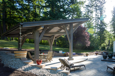 Mountain style backyard concrete paver patio photo in Portland with a pergola