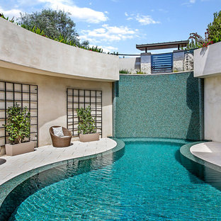 This is an example of a large contemporary courtyard patio in Los Angeles with natural stone pavers and no cover.
