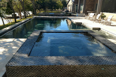 Large arts and crafts backyard custom-shaped natural pool in Houston with a hot tub and natural stone pavers.