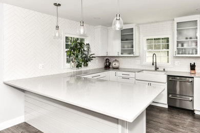 Eat-in kitchen - large modern galley vinyl floor and brown floor eat-in kitchen idea in DC Metro with a farmhouse sink, shaker cabinets, white cabinets, quartzite countertops, white backsplash, porcelain backsplash, stainless steel appliances, an island and gray countertops