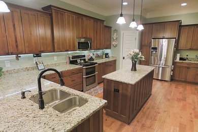 Inspiration for a large timeless l-shaped light wood floor and brown floor eat-in kitchen remodel in Other with an undermount sink, shaker cabinets, medium tone wood cabinets, granite countertops, white backsplash, glass tile backsplash, stainless steel appliances, an island and gray countertops