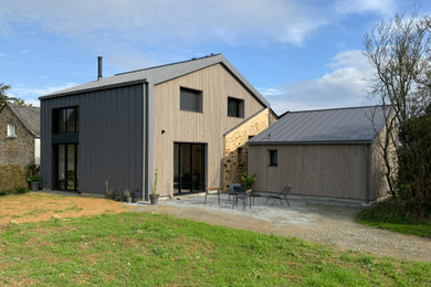 Cette photo montre une façade de maison tendance en bois et planches et couvre-joints à deux étages et plus avec un toit à deux pans, un toit en métal et un toit gris.