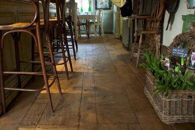 Farmhouse home bar in Other with medium hardwood flooring.