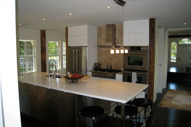 Mid-sized minimalist single-wall dark wood floor eat-in kitchen photo in Burlington with a double-bowl sink, flat-panel cabinets, white cabinets, solid surface countertops, beige backsplash, stone tile backsplash, stainless steel appliances and an island