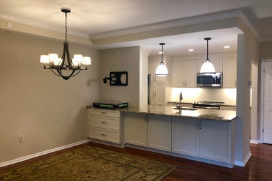 Mid-sized elegant galley dark wood floor and brown floor eat-in kitchen photo in Philadelphia with an undermount sink, beaded inset cabinets, white cabinets, granite countertops, beige backsplash, ceramic backsplash, stainless steel appliances, a peninsula and green countertops