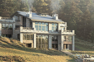 Foto de fachada de casa beige rústica extra grande de tres plantas con revestimiento de piedra y tejado de metal