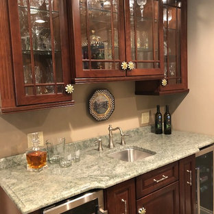 ニューヨークのトラディショナルスタイルのおしゃれなウェットバー (アンダーカウンターシンク、レイズドパネル扉のキャビネット、中間色木目調キャビネット、御影石カウンター、セラミックタイルの床、ベージュの床、緑のキッチンカウンター) の写真