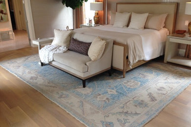 Modelo de habitación de invitados de tamaño medio sin chimenea con paredes beige y suelo de madera clara
