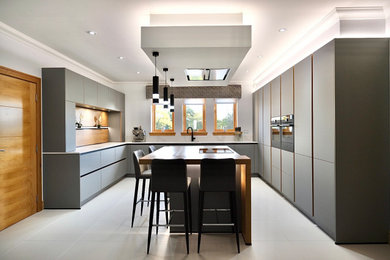 Offene, Große Rustikale Küche mit grauen Schränken, schwarzen Elektrogeräten, Kücheninsel und weißer Arbeitsplatte in Sonstige