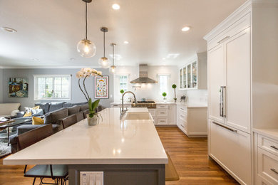 Large transitional u-shaped medium tone wood floor open concept kitchen photo in San Francisco with a farmhouse sink, shaker cabinets, white cabinets, white backsplash, subway tile backsplash, an island, quartz countertops and stainless steel appliances