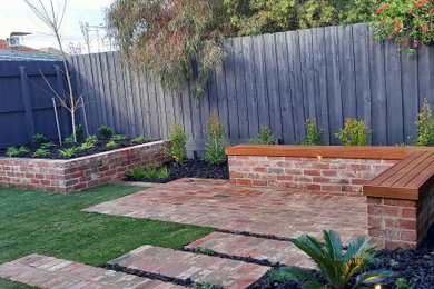 Inspiration for a mid-sized backyard full sun garden in Melbourne with brick pavers and a wood fence.