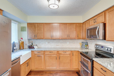 Eat-in kitchen - mid-sized transitional u-shaped medium tone wood floor and brown floor eat-in kitchen idea in Kansas City with a farmhouse sink, shaker cabinets, medium tone wood cabinets, granite countertops, beige backsplash, subway tile backsplash and stainless steel appliances