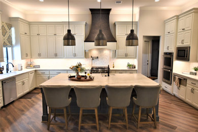 Large transitional u-shaped porcelain tile eat-in kitchen photo in Houston with an undermount sink, raised-panel cabinets, white cabinets, quartzite countertops, white backsplash, stone tile backsplash, stainless steel appliances and an island