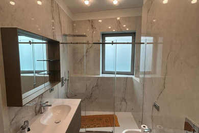 ミラノにあるお手頃価格の中くらいなモダンスタイルのおしゃれなバスルーム (浴槽なし) (フラットパネル扉のキャビネット、白いタイル、磁器タイル、白い壁、塗装フローリング、一体型シンク、白い床、引戸のシャワー、白い洗面カウンター、洗面台1つ、フローティング洗面台) の写真