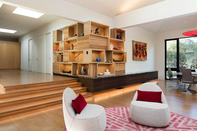 This is an example of a large contemporary open concept living room in San Francisco with a library, white walls, medium hardwood floors and brown floor.
