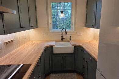 Example of a small minimalist u-shaped enclosed kitchen design in Other with shaker cabinets, green cabinets and wood countertops