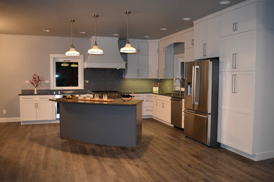 Eat-in kitchen - large transitional l-shaped laminate floor and gray floor eat-in kitchen idea in Seattle with an undermount sink, shaker cabinets, white cabinets, quartz countertops, blue backsplash, glass tile backsplash, stainless steel appliances and an island