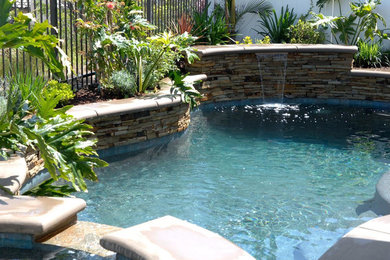 Modelo de piscinas y jacuzzis alargados tradicionales renovados de tamaño medio a medida en patio trasero con adoquines de hormigón