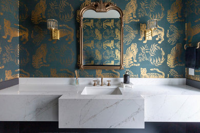 Mid-sized elegant porcelain tile and black floor powder room photo in New York with a two-piece toilet, green walls, a drop-in sink, quartz countertops, white countertops and a built-in vanity