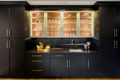 Example of a mid-sized trendy single-wall medium tone wood floor and brown floor wet bar design in New York with an undermount sink, recessed-panel cabinets, black cabinets, quartz countertops, black backsplash, quartz backsplash and black countertops