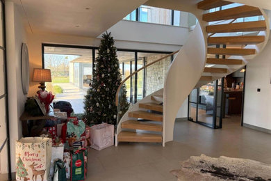 Example of a mid-sized cottage wooden curved open, glass railing and wallpaper staircase design in Berkshire