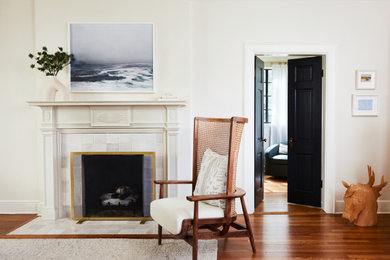 Foto de salón cerrado de tamaño medio con paredes beige, suelo de madera en tonos medios, marco de chimenea de baldosas y/o azulejos y televisor retractable