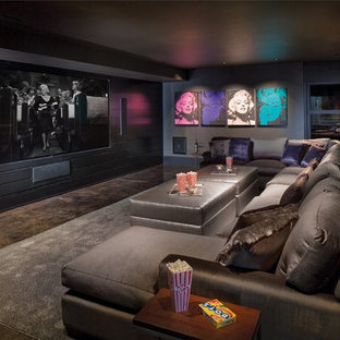 Cette image montre une salle de cinéma design ouverte avec un mur noir, moquette, un écran de projection et un sol multicolore.