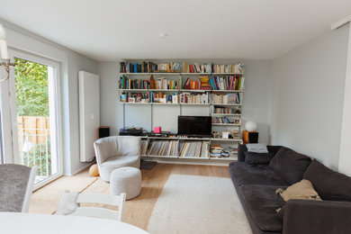 Offenes Modernes Wohnzimmer mit weißer Wandfarbe, Eck-TV und braunem Boden in Frankfurt am Main