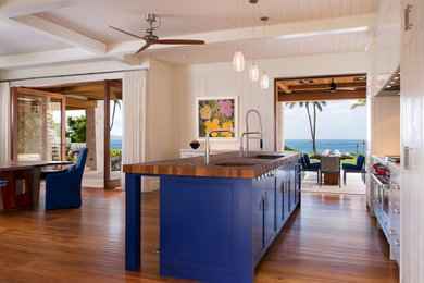 Inspiration for a mid-sized tropical galley medium tone wood floor and brown floor eat-in kitchen remodel in Hawaii with an undermount sink, flat-panel cabinets, white cabinets, wood countertops, subway tile backsplash, an island, beige backsplash and stainless steel appliances