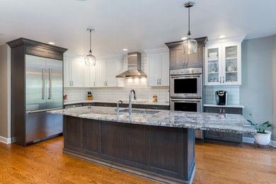 Mid-sized transitional l-shaped medium tone wood floor open concept kitchen photo in Chicago with a single-bowl sink, shaker cabinets, white cabinets, granite countertops, white backsplash, subway tile backsplash, stainless steel appliances and an island