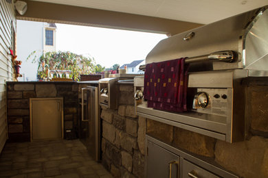 Example of a large classic backyard concrete paver patio kitchen design in Other with a roof extension