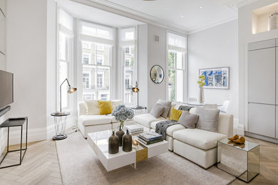Photo of a mid-sized transitional open concept living room in London with white walls, a wall-mounted tv, beige floor and light hardwood floors.