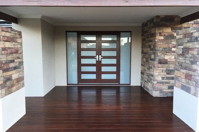Imagen de puerta principal actual pequeña con paredes beige, suelo de madera en tonos medios, puerta doble, puerta de madera oscura y suelo marrón