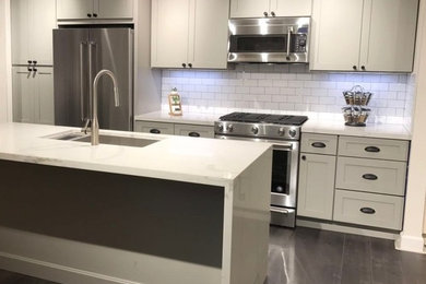 Large transitional single-wall kitchen in San Francisco with an undermount sink, shaker cabinets, white cabinets, marble benchtops, white splashback, subway tile splashback, stainless steel appliances, dark hardwood floors, with island and brown floor.