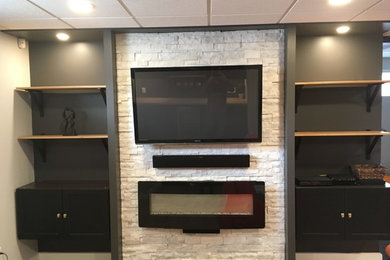 Example of a mid-sized classic enclosed carpeted and gray floor living room design in Other with black walls, a ribbon fireplace, a stone fireplace and a wall-mounted tv