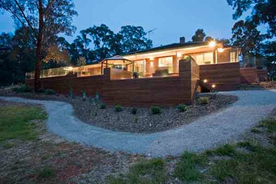 Expansive contemporary backyard deck in Melbourne with a container garden and a pergola.