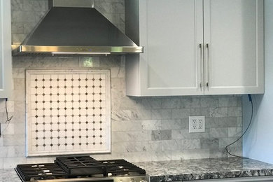 Inspiration for a small timeless galley porcelain tile and brown floor enclosed kitchen remodel in Los Angeles with an undermount sink, shaker cabinets, gray cabinets, quartz countertops, gray backsplash, marble backsplash, stainless steel appliances and black countertops
