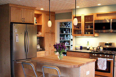 Example of a mid-sized transitional l-shaped eat-in kitchen design in Boston with a farmhouse sink, shaker cabinets, light wood cabinets, granite countertops, black backsplash, stone slab backsplash, stainless steel appliances and an island