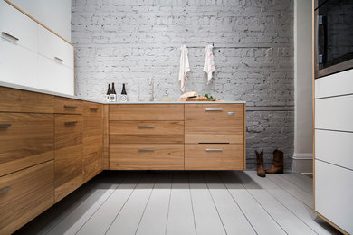 Trendy l-shaped painted wood floor and gray floor enclosed kitchen photo in Montreal with an undermount sink, flat-panel cabinets, medium tone wood cabinets, laminate countertops, stainless steel appliances, gray backsplash and brick backsplash