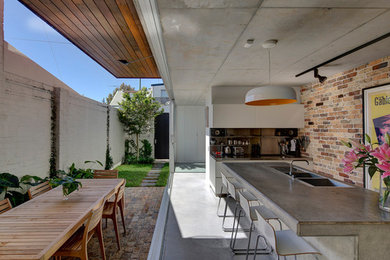 Photo of a mid-sized contemporary eat-in kitchen in Sydney with a drop-in sink, concrete benchtops, metal splashback, stainless steel appliances, concrete floors and with island.