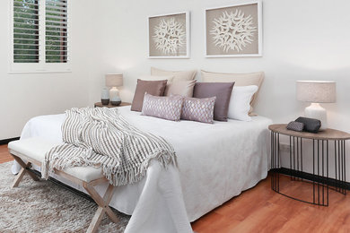 Design ideas for a mid-sized transitional master bedroom in Sydney with white walls, light hardwood floors and orange floor.
