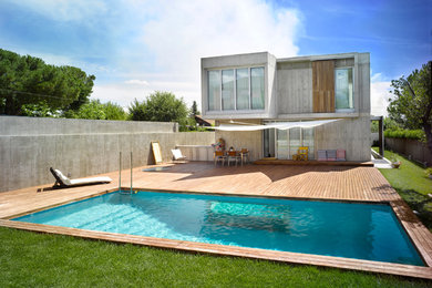 Foto de casa de la piscina y piscina alargada moderna grande rectangular en patio trasero con entablado