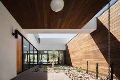 Large minimalist concrete floor, gray floor, wood ceiling and wood wall entryway photo in Phoenix with multicolored walls and a light wood front door